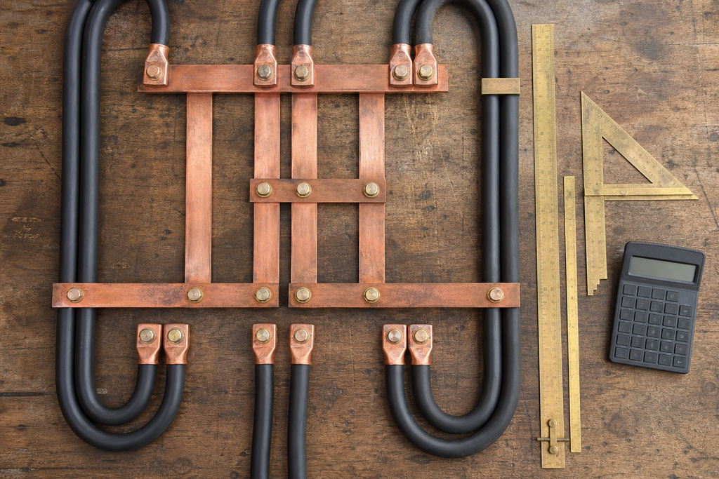 Copper and black wiring components arranged on a wooden surface with measuring tools, relevant for campground electrification.