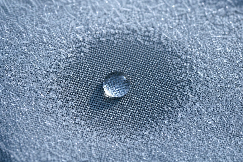Close-up of a water droplet resting on a textured graphene sleeping bag fabric.
